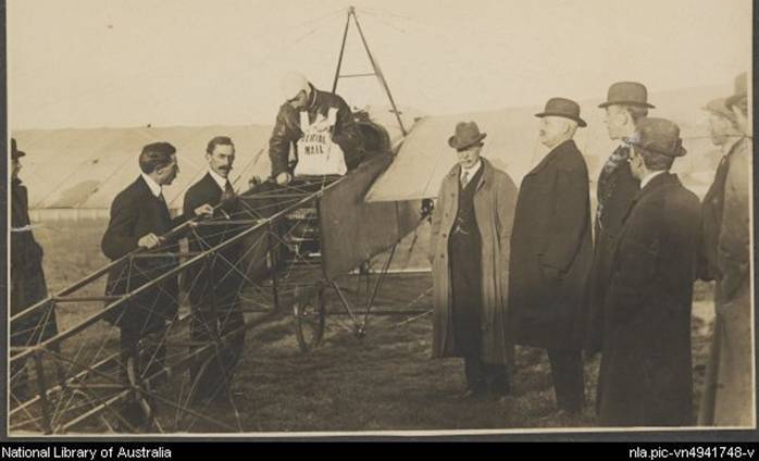 Darge, Algernon, 1878-1941. Maurice Guillaux in his Bleriot XI monoplane holding aerial mail bag at the Agricultural Society's show grounds before flying to Sydney on first air mail delivery, Melbourne, 16 July 1914 [picture]