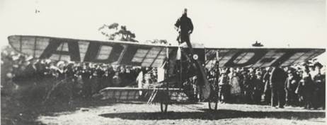  First flight from Melbourne to Sydney showing pilot Maurice Guillaux standing on a Bleriot monoplane with a 50 horsepower Gnome engine, Wangaratta, July 1914 [picture].